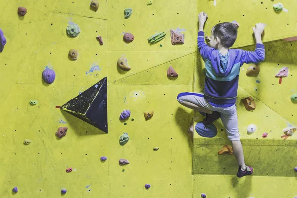 Little boy climbing a rock wall indoor. Concept of sport life.