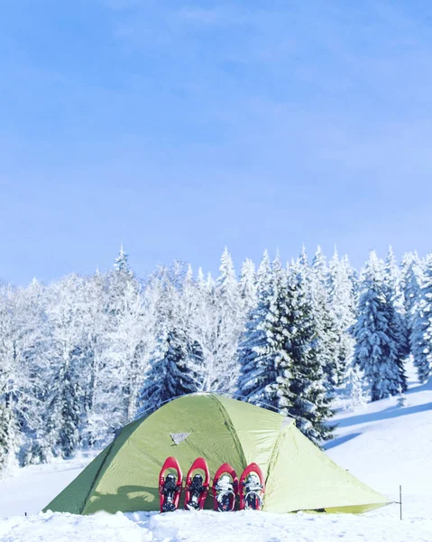 Winter hike in the mountains. Snowshoes are in the snow near the tent.