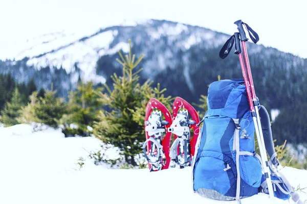 Winter hiking in the mountains with a tent in snowshoes.