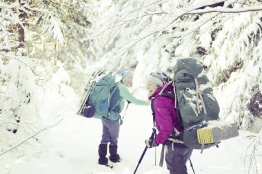 İki kız kış ormanda yürüyor.