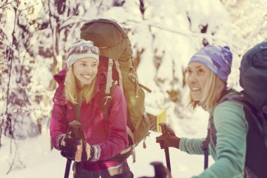 İki kız kış ormanda yürüyor.