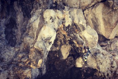 Kız kaya tırmanışçısı zor yol uçurumlarda tırmanıyor..