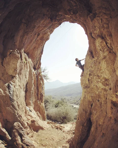Hombre escalador colgando con una mano en ruta desafiante en —  Fotos de Stock