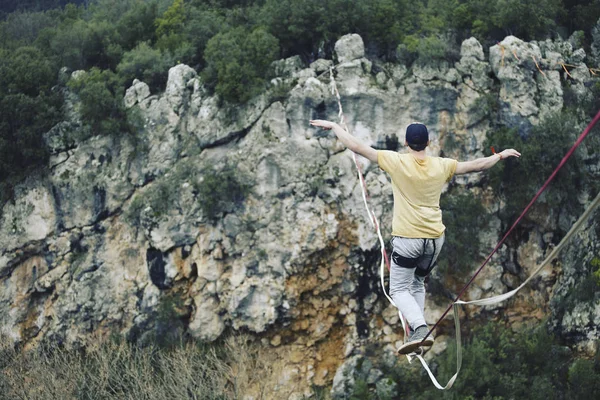 Un hombre camina a lo largo de una honda estirada. Highline en la montaña —  Fotos de Stock