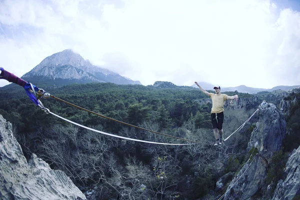 A man is walking along a stretched sling. Highline in the mounta