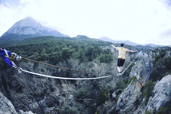 Un hombre camina a lo largo de una honda estirada. Highline en la montaña —  Fotos de Stock