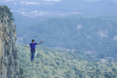 Bir adam gergin bir sapan boyunca yürüyor. Mounta Highline