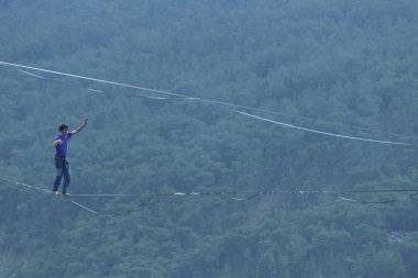 Bir adam gergin bir sapan boyunca yürüyor. Mounta Highline