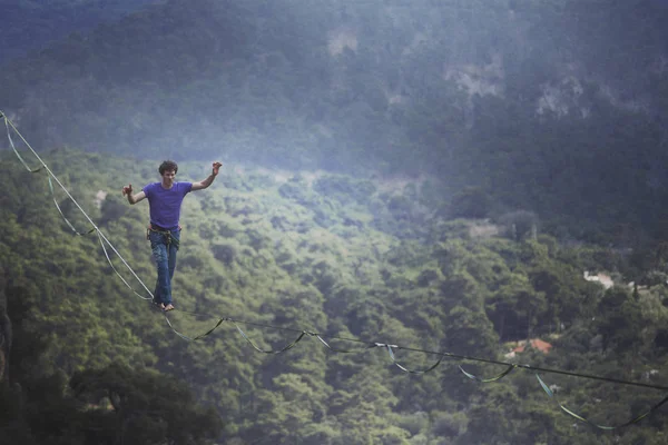 Un hombre camina a lo largo de una honda estirada. Highline en la montaña —  Fotos de Stock