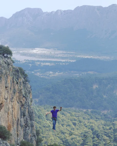 Ένας άντρας περπατά κατά μήκος μιας τεντωμένη σφεντόνα. Χάιλάιν στο βουνό — Φωτογραφία Αρχείου