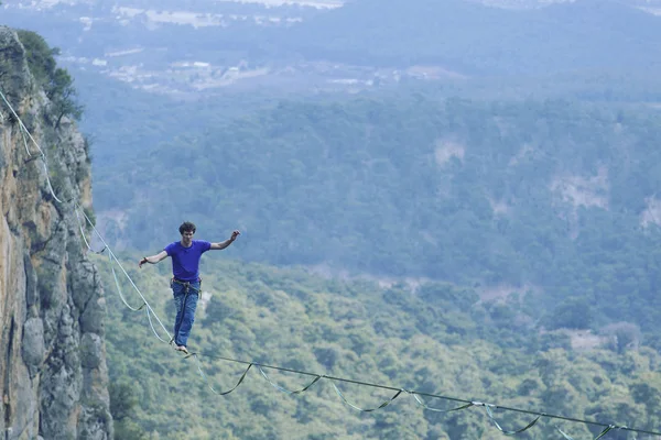 Un uomo sta camminando lungo una fionda allungata. Highline nel monte — Foto Stock