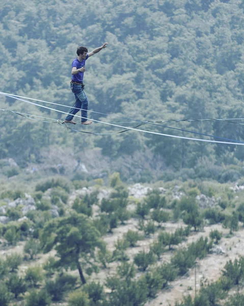 Un hombre camina a lo largo de una honda estirada. Highline en la montaña —  Fotos de Stock