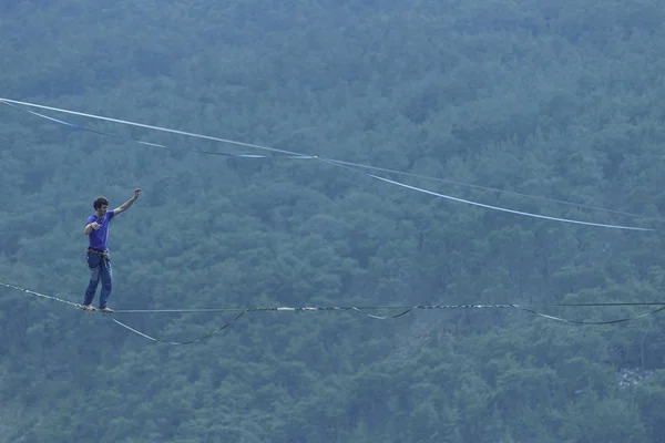 Mężczyzna chodzi wzdłuż rozciągniętego procy. Highline w górach — Zdjęcie stockowe