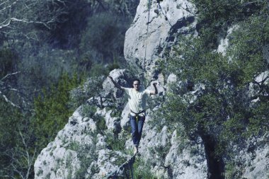 Bir adam gergin bir sapan boyunca yürüyor. Mounta Highline