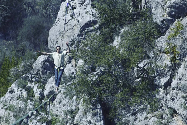 Un hombre camina a lo largo de una honda estirada. Highline en la montaña —  Fotos de Stock