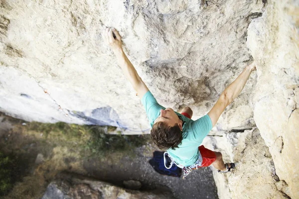 Hombre escalador de rocas. Escalador de rocas sube a una pared rocosa. El hombre hace —  Fotos de Stock