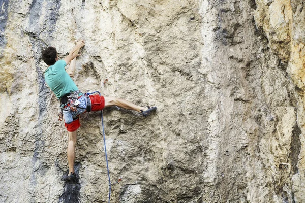 Hombre escalador de rocas. Escalador de rocas sube a una pared rocosa. El hombre hace — Foto de Stock