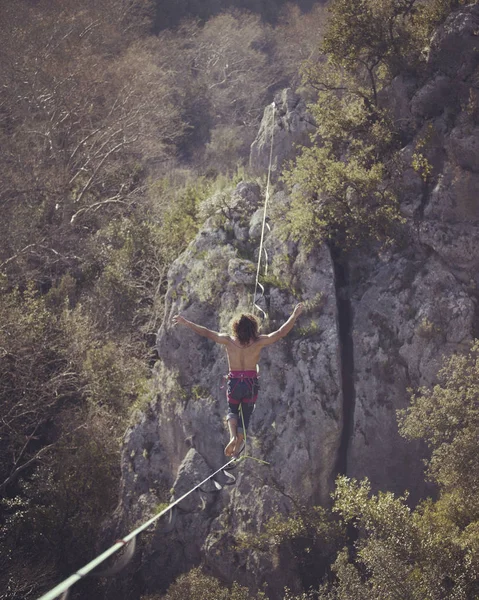 Un hombre camina a lo largo de una honda estirada. Highline en la montaña — Foto de Stock