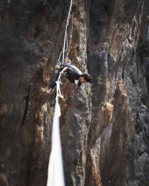 Bir adam gergin bir sapan boyunca yürüyor. Mounta Highline