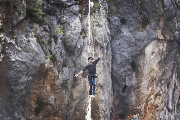 Mężczyzna chodzi wzdłuż rozciągniętego procy. Highline w górach — Zdjęcie stockowe