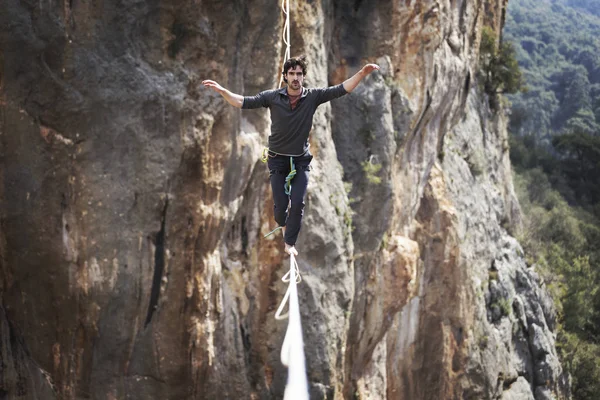 Un hombre camina a lo largo de una honda estirada. Highline en la montaña — Foto de Stock