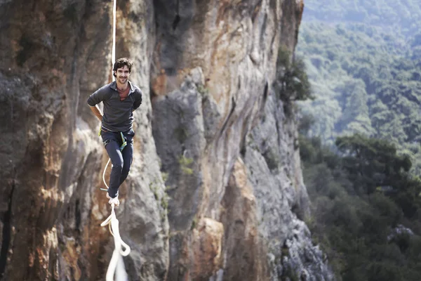 Un hombre camina a lo largo de una honda estirada. Highline en la montaña — Foto de Stock