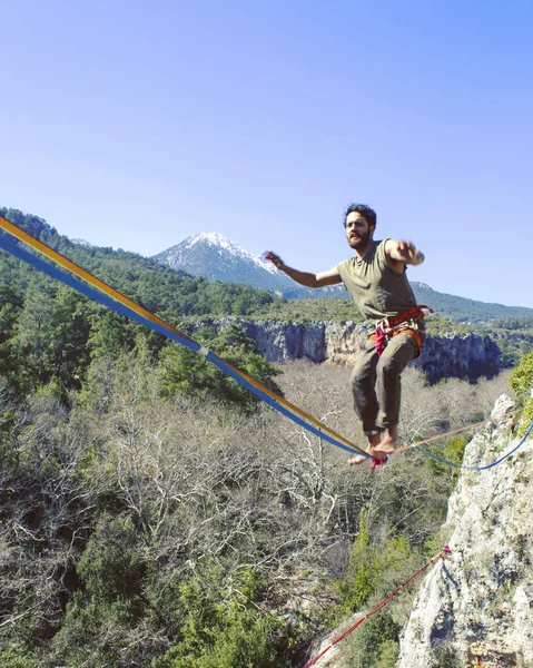 Un hombre camina a lo largo de una honda estirada. Highline en la montaña — Foto de Stock