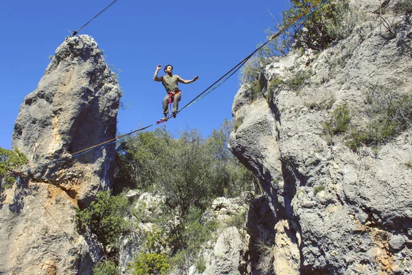 Mężczyzna chodzi wzdłuż rozciągniętego procy. Highline w górach — Zdjęcie stockowe