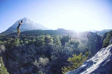 Bir adam gergin bir sapan boyunca yürüyor. Mounta Highline
