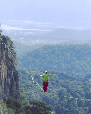 Bir adam gergin bir sapan boyunca yürüyor. Mounta Highline