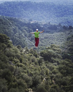 Bir adam gergin bir sapan boyunca yürüyor. Mounta Highline