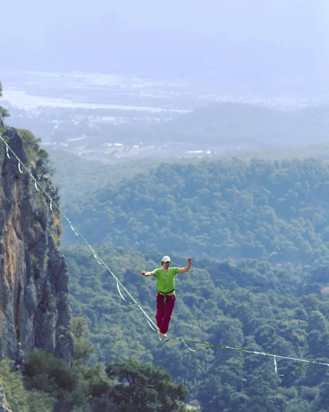 A man is walking along a stretched sling. Highline in the mounta — Stock Photo, Image