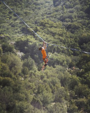 Bir adam gergin bir sapan boyunca yürüyor. Mounta Highline