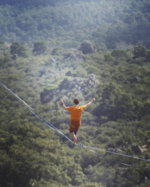 Bir adam gergin bir sapan boyunca yürüyor. Mounta Highline