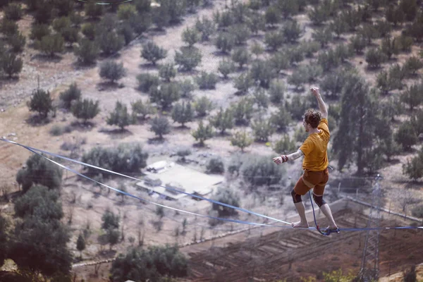 Un hombre camina a lo largo de una honda estirada. Highline en la montaña — Foto de Stock