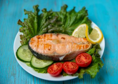 Büyük bir parça somon, marul, domates ve limon.