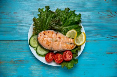 Büyük bir parça somon, marul, domates ve limon.