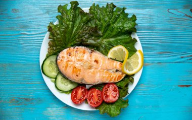 Büyük bir parça somon, marul, domates ve limon.