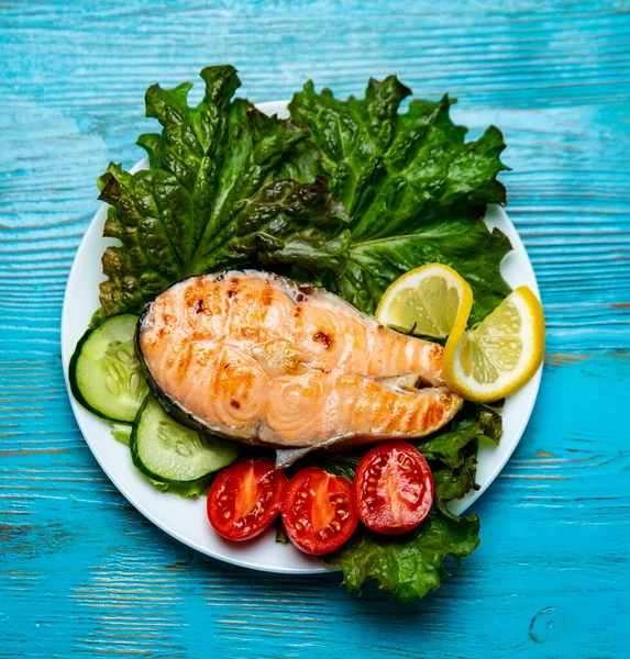 Büyük bir parça somon, marul, domates ve limon.