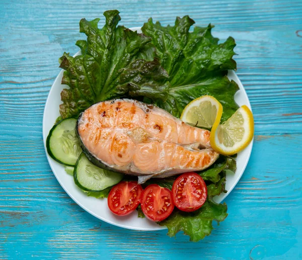 Büyük bir parça somon, marul, domates ve limon.