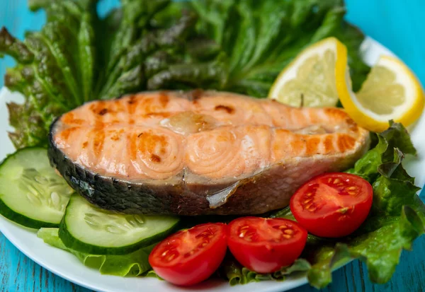 Büyük bir parça somon, marul, domates ve limon.
