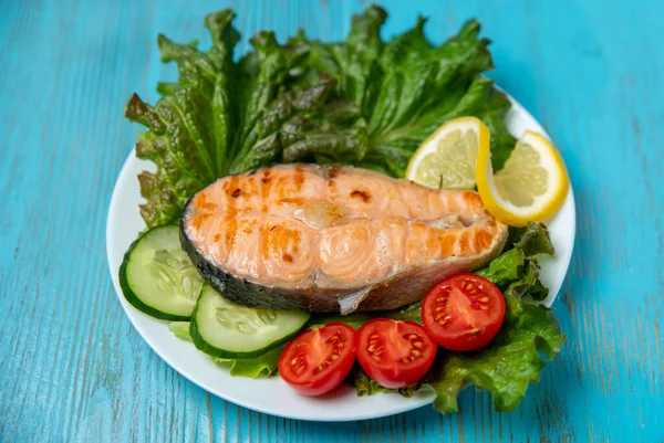 Büyük bir parça somon, marul, domates ve limon.