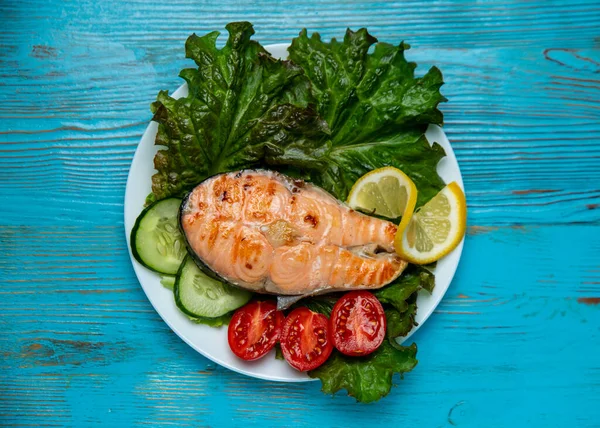 Büyük bir parça somon, marul, domates ve limon.