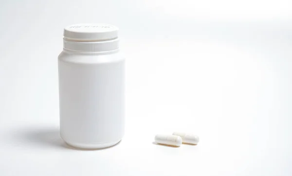 白い背景の丸薬と近くの白い丸薬の碑文のない白いプラスチックチューブ — ストック写真