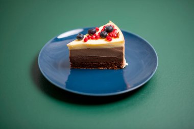 Yeşil arka planda mavi tabakta çikolatalı pasta.