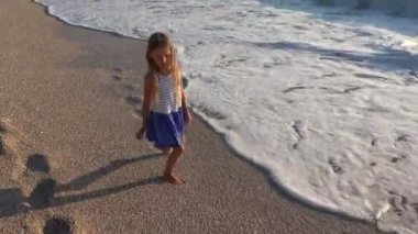 Kumsalda, oynayan 4 k çocuk deniz dalgaları görünümü, kız'nde günbatımı sahil şeridi üzerinde yürüyüş