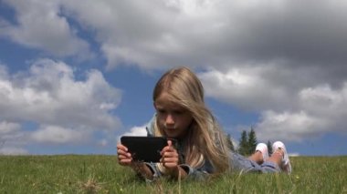 4k kız portre oynarken Tablet, çayır çimen Park Smartphone kullanarak çocuk