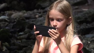 Tablet açık, oynayan çocuk portre bir nehir tarafından 4 k Smartphone kullanarak kız yüz