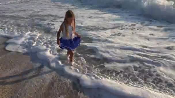 在日落时分在沙滩上玩耍的女孩 在海岸线上漫步在海浪中的孩子 — 图库视频影像