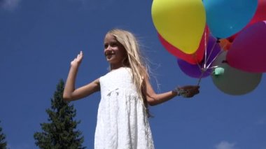 Oynayan çocuk balonlar, veda sallıyor ve bir öpücük, kız parkta gönderme